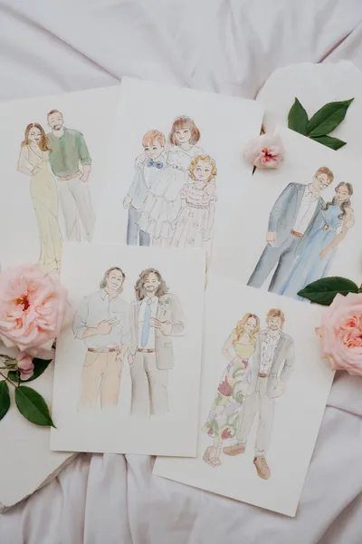 Flat lay of soft watercolour guest portraits of couples and a family among pink garden roses, by Adore by Lissy