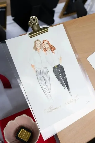Watercolour fashion illustration of two women in white shirts and trousers with gold calligraphy names, by Graced Goods