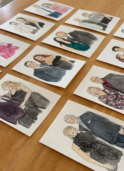 Rows of watercolour and ink live guest portraits of couples in evening wear laid on a timber table, by Just Sketched Art