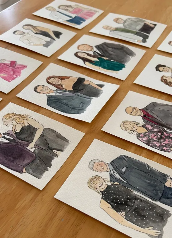 Rows of watercolour and ink live guest portraits of couples in evening wear laid on a timber table, by Just Sketched Art