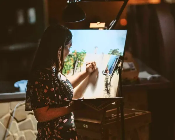 Artist Natalie Lotriet painting a wedding scene in acrylic at an easel during an evening reception, by Canvas by Design